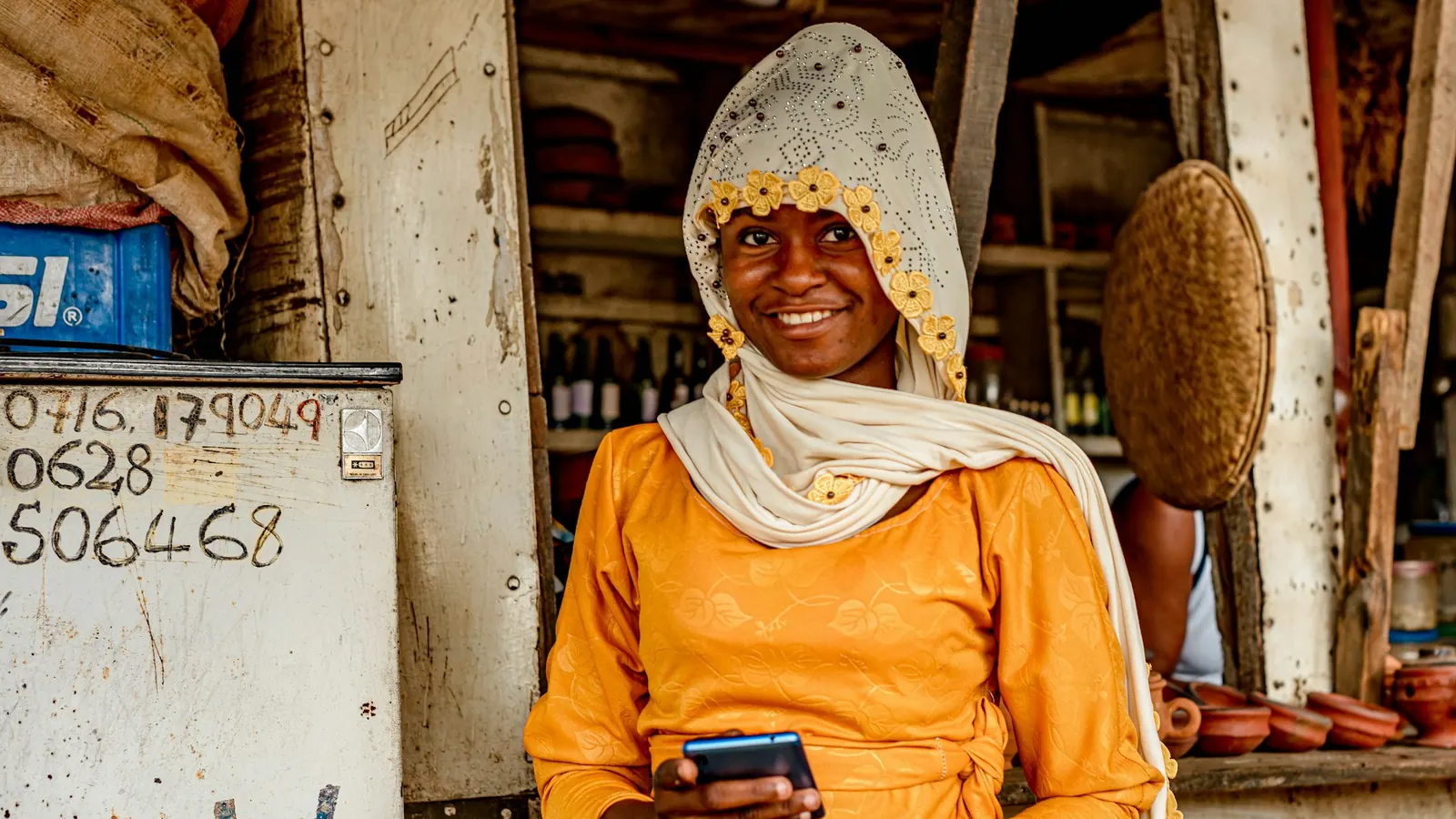 Smiling shop owner holding a mobile phone at her stall