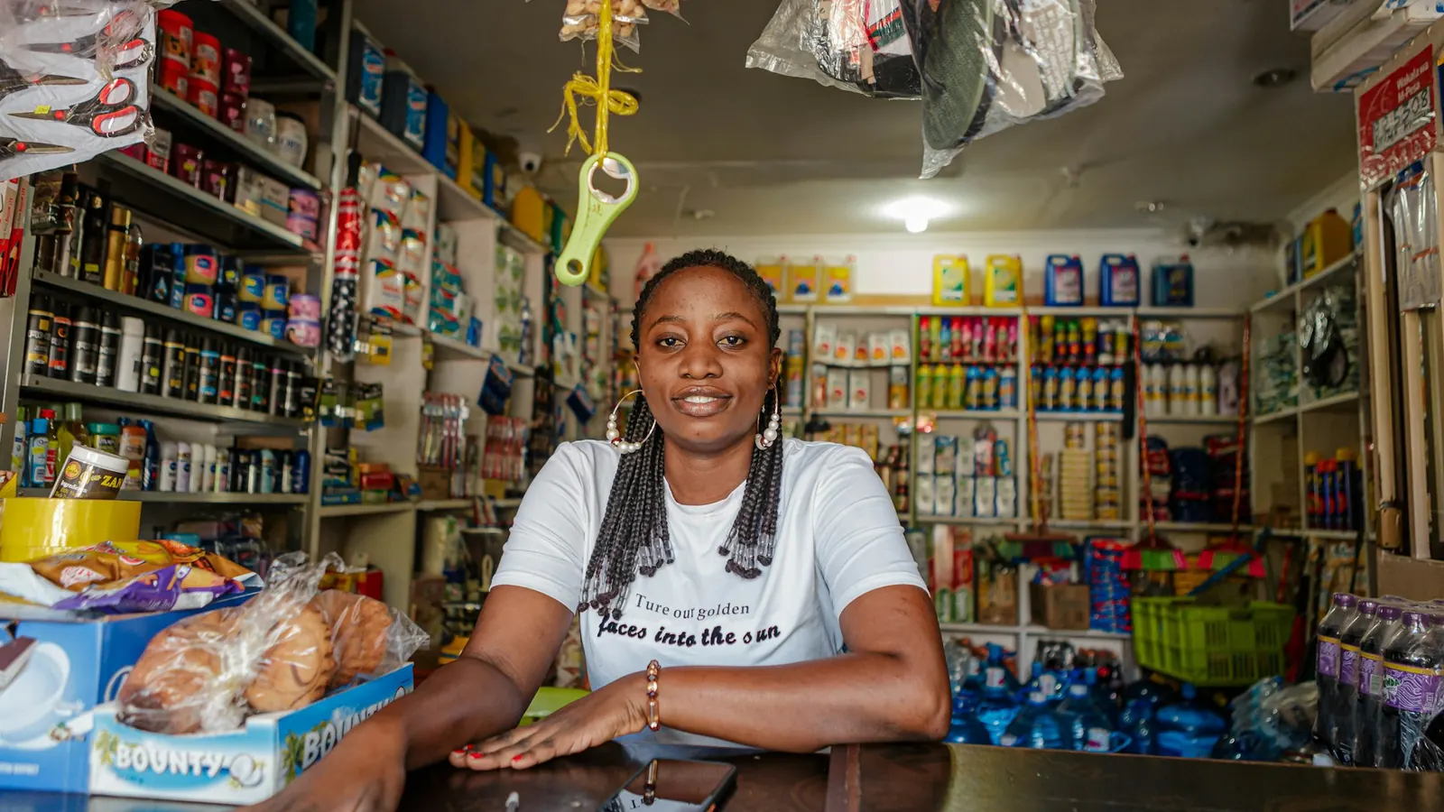 Smiling small business owner at the counter of her well-stocked shop