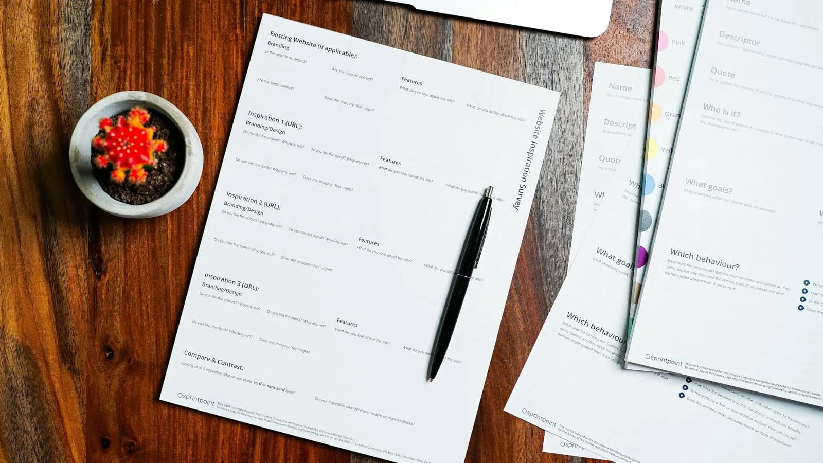Printed business documents and a pen laid out on a wooden desk for review